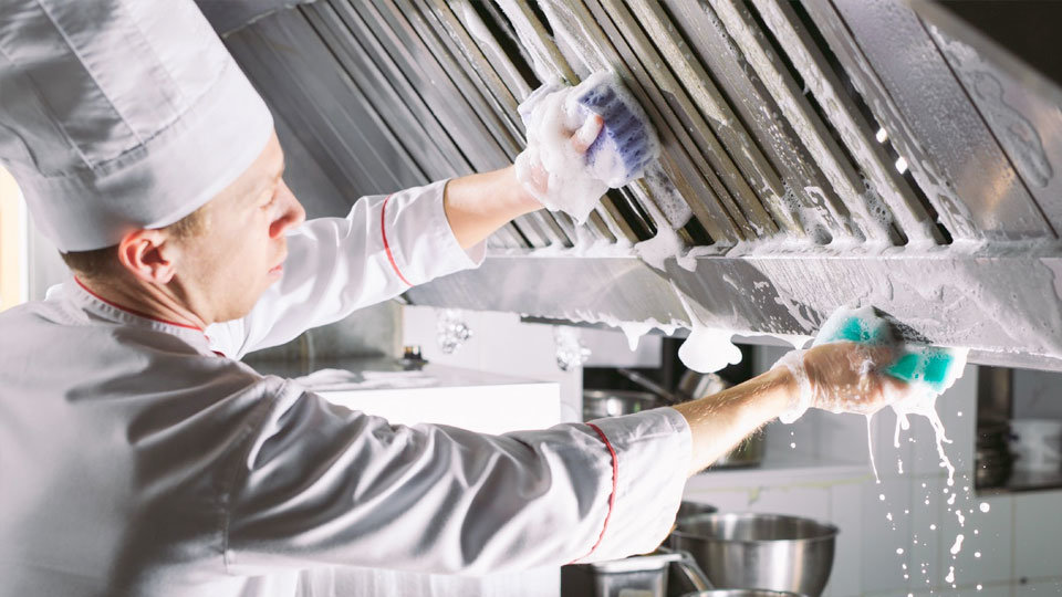 chef employing safety measures while cleaning grill hood