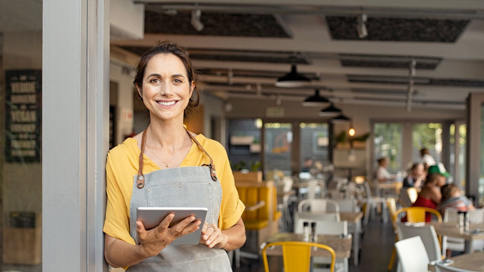 kitchen staff member, smiling while using ipad for smart ai seating in restaurant