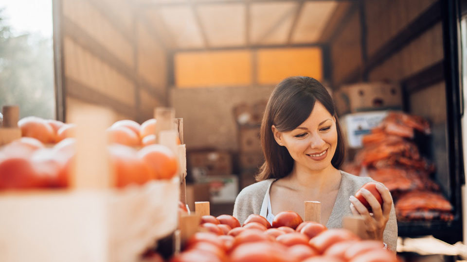 woman sorting through box of tomatoes in kitchen pantry