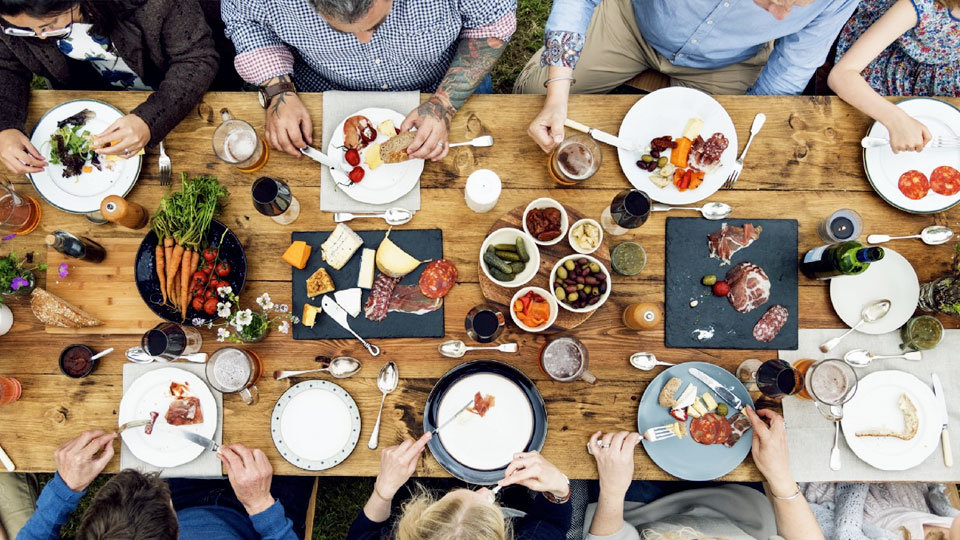 large table of food with people sitting and eating at it